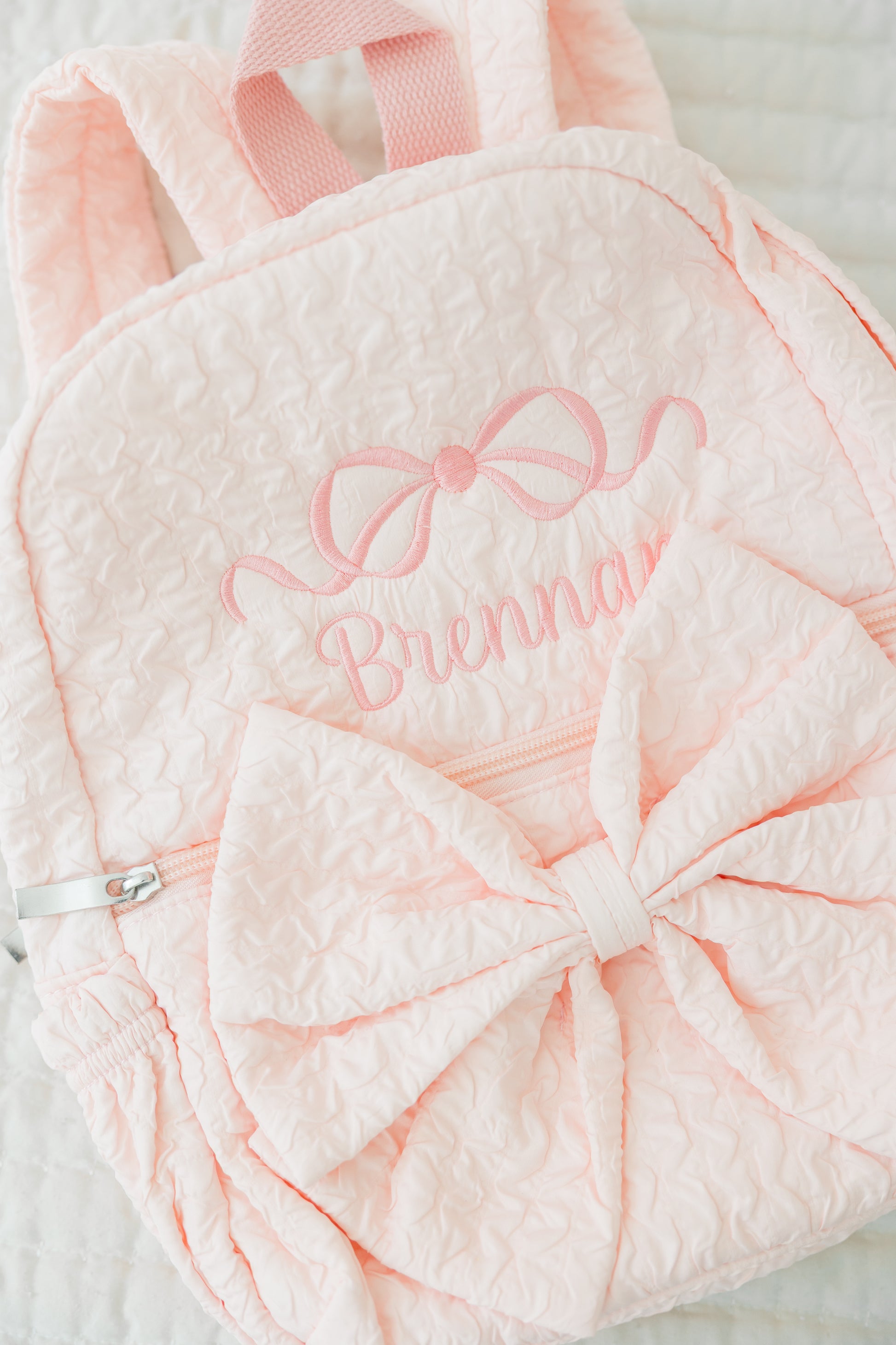Pink textured bag with bow and embroidered name on a light background