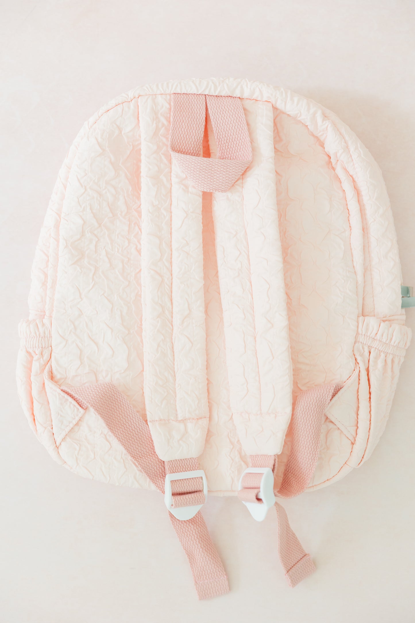Pink baby carrier with quilted backrest on a light background