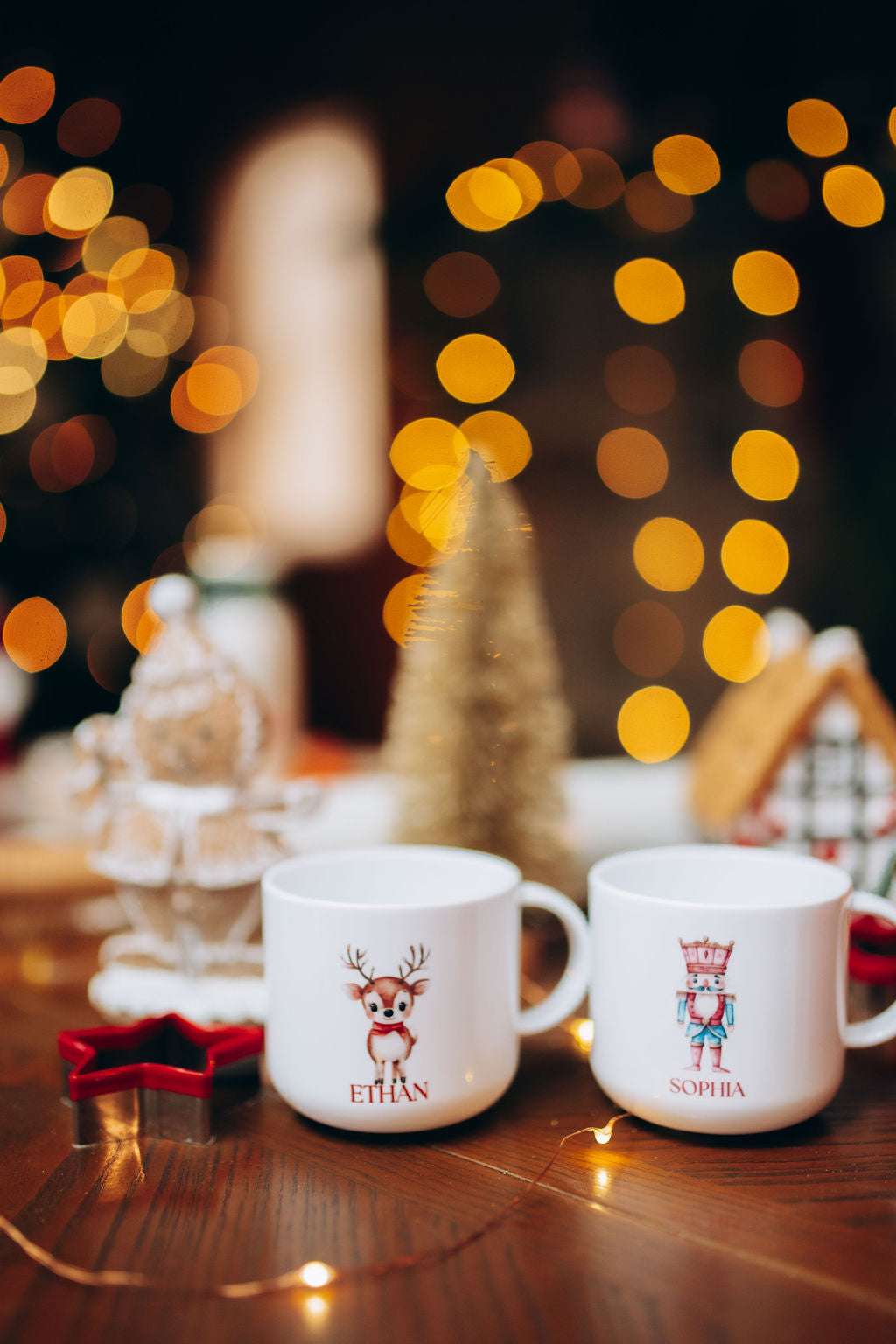 Two mugs with personalized names on a festive background with lights and decorations.