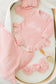Pink baby outfit with ruffled details on a white surface