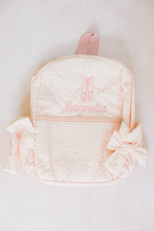 Pink backpack with 'Magnolia' embroidery on a white background