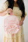 Person holding a pink backpack with a large bow and embroidered name against a plain background