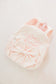 Pink plush backpack with decorative bow on a light gray background