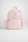 Child in pink outfit with backpack walking outdoors on grass